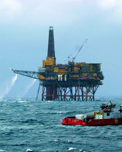 Plataforma petrolífera en el mar del Norte y uno de sus barcos de apoyo, en junio de 2004. Los expertos dicen que el consumo de combustibles fósiles aviva el calentamiento. Nick Cobbing / Greenpeace