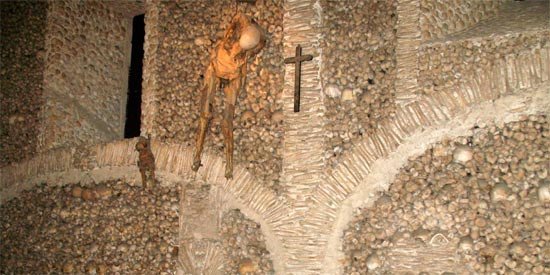 Dos esqueletos, uno el de un niño, cuelgan junto a la pared derecha de la capilla de los huesos. Imagen de Tomás Alvarez/Guiarte.com