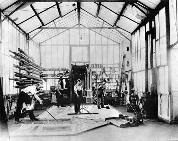 Georges Méliès pintando un decorado en el suelo de su estudio, con un dibujo preparatorio en una de las manos. La Cinémathèque française. Foto Stéphane Dabrowski