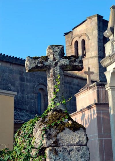 La iglesia de Santiago, en Barbadelo, Lugo, asoma por encima de las lápidas del cementerio.