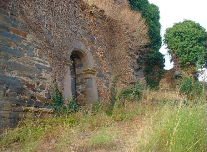 Imagen de la ermita en el reciente pasado, dominada por arbustos y hiedras, aunque manteniendo una recia estatrura de piedra
