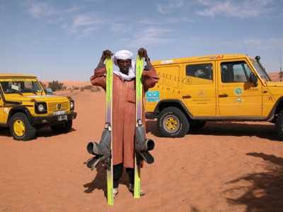 Un tuareg, ofrece  esquís en alquiler, para utilizarlos en la arena. guiarte.com