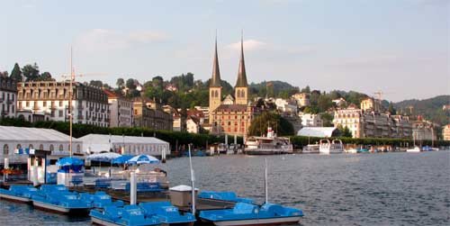Las aguzadas flechas de la Hofkirche, en Lucerna, dominando el paisaje, a la orilla del lago. Guiarte.com. Copyright