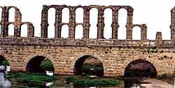 El acueducto de los Milagros se recorta sobre la silueta del puente romano sobre el Albarregas. Foto guiarte