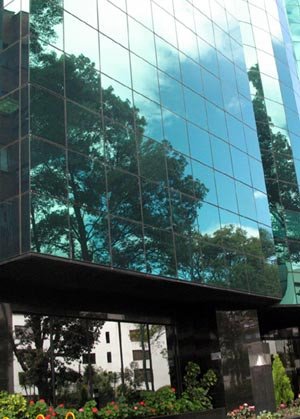 La magnífica vegetación de Bogotá se refleja en la fachada de cristal de este moderno edificio capitalino. Imagen de guiarte.com.