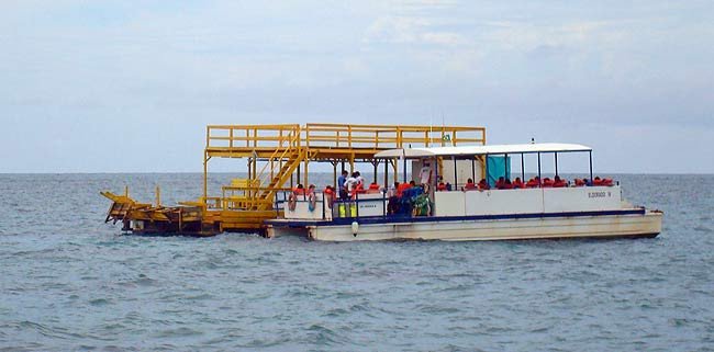 Catamarán en Maracajaú con plataforma operacional de desembarco de turistas en los corales.
